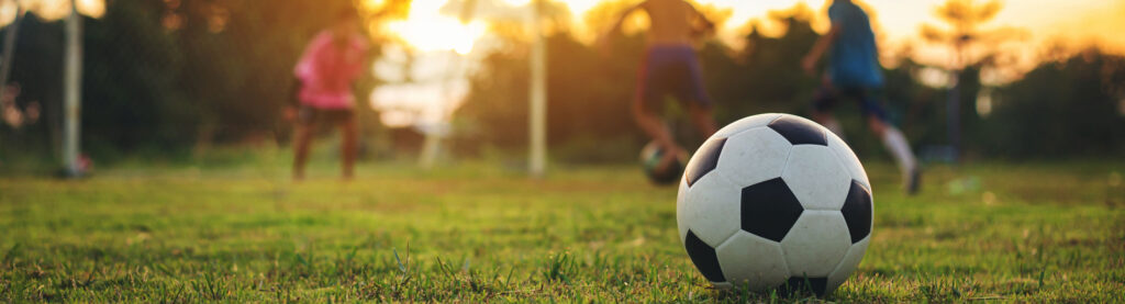 Close-up of soccer ball with kids playing in the background