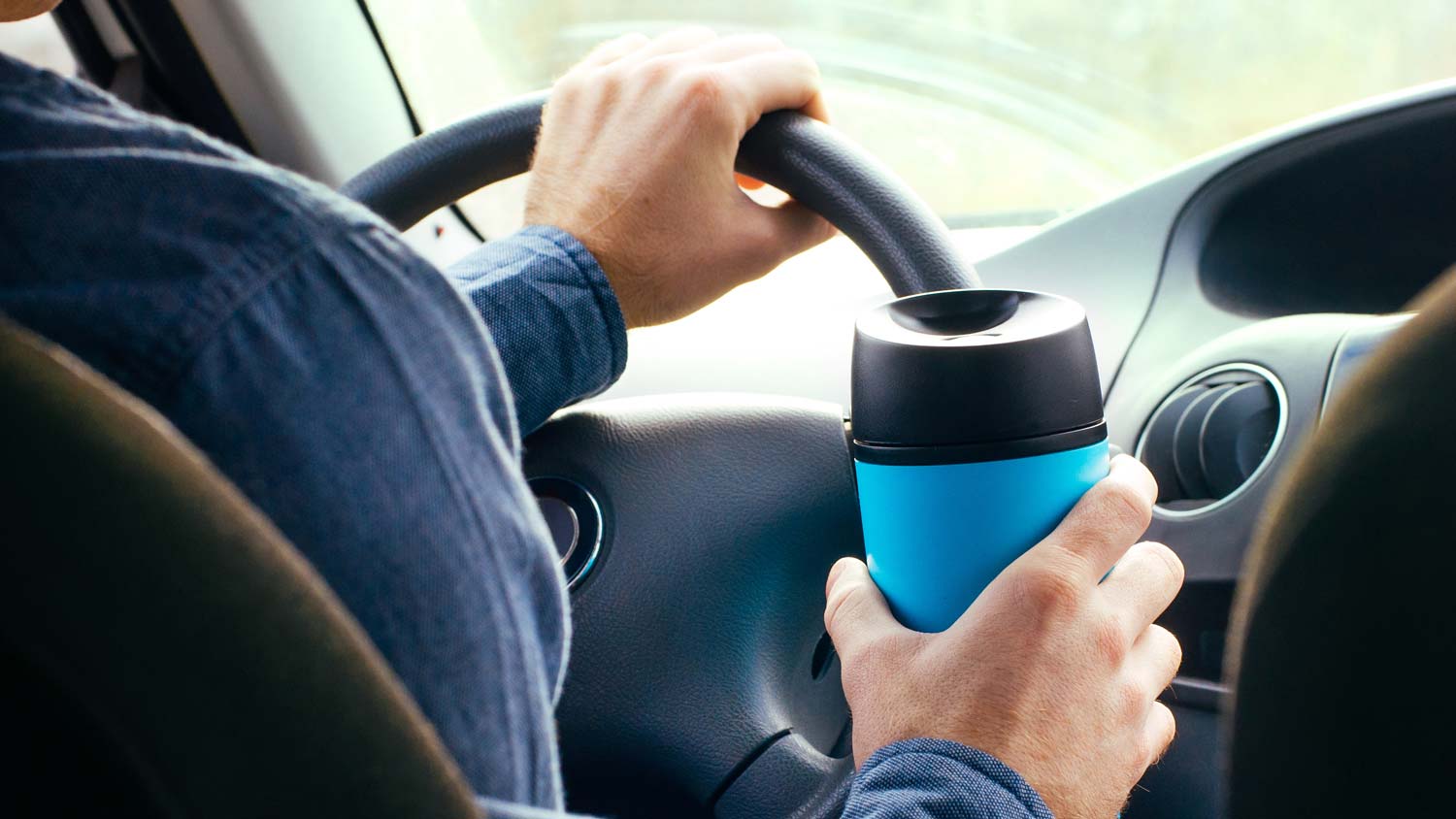 Man driving truck holding thermos